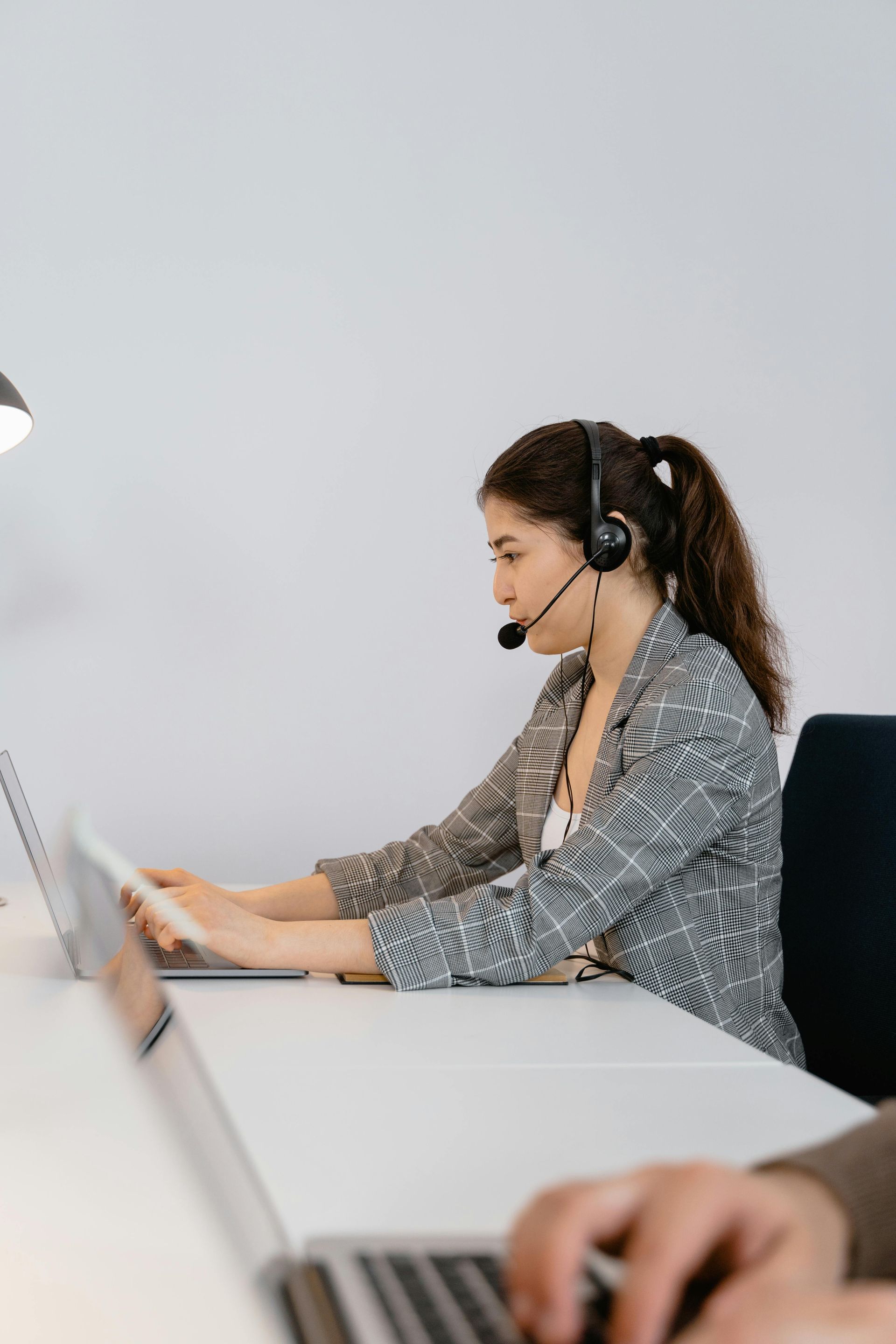 Woman wearing a headset working at a laptop in an office