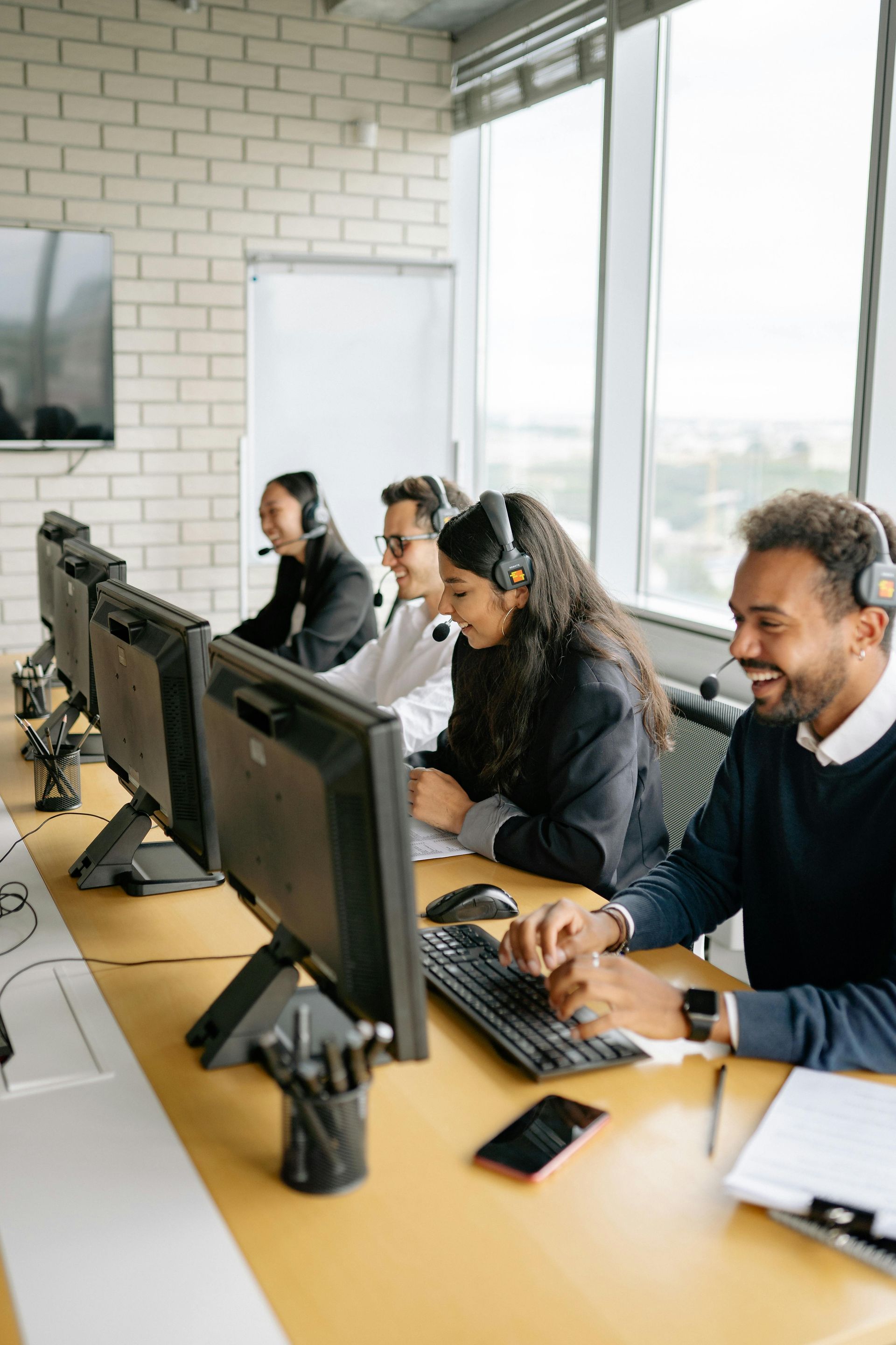 Call center team wearing headsets working at computers in a bright office