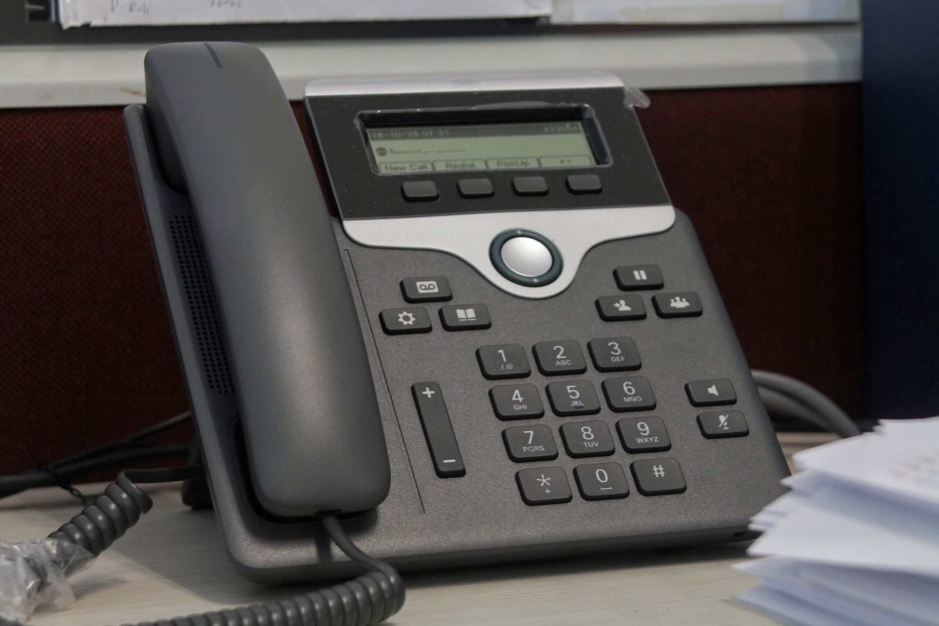 Desk office phone with keypad and corded handset on a table