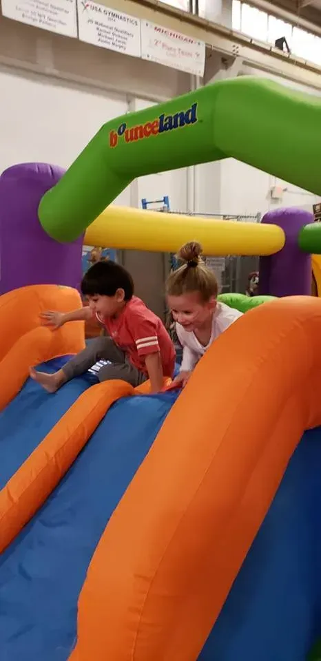 a boy and a girl are playing on an inflatable slide