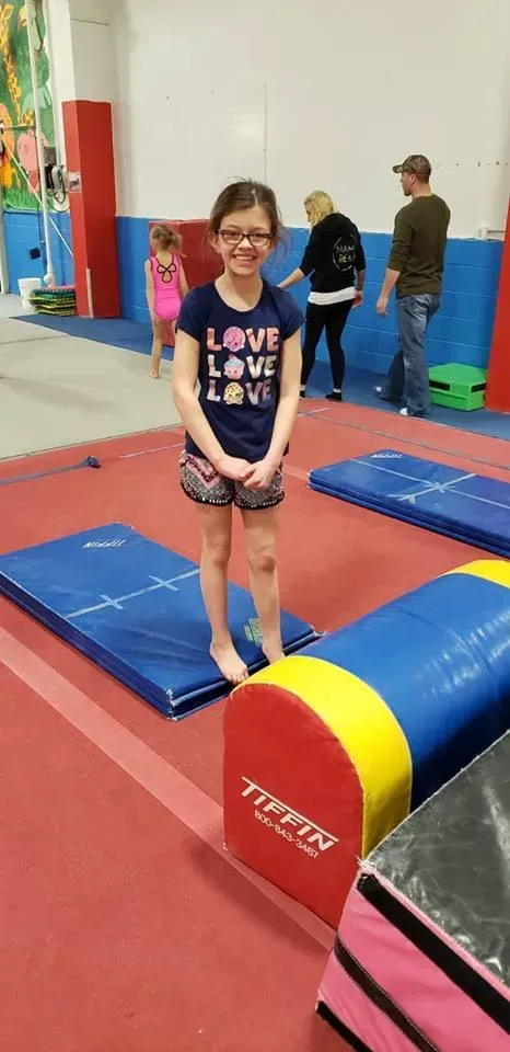 a young girl is standing on a balance beam in a gym