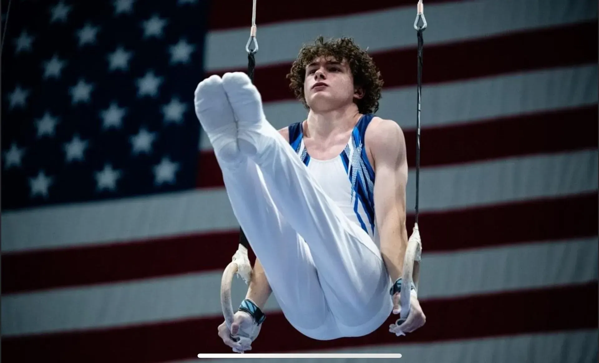 a gymnast is performing on rings in front of an american flag
