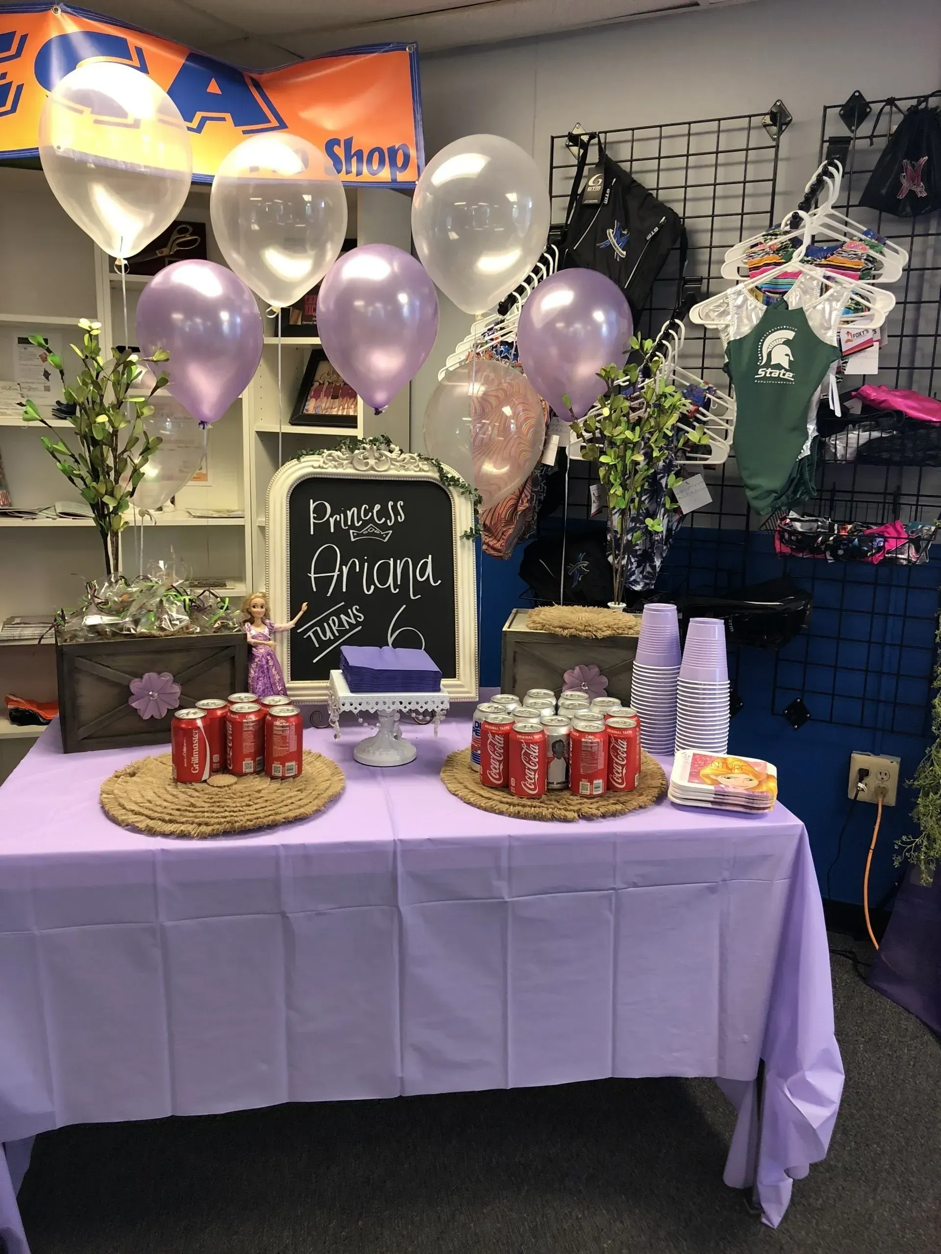 a table with a purple table cloth and balloons on it