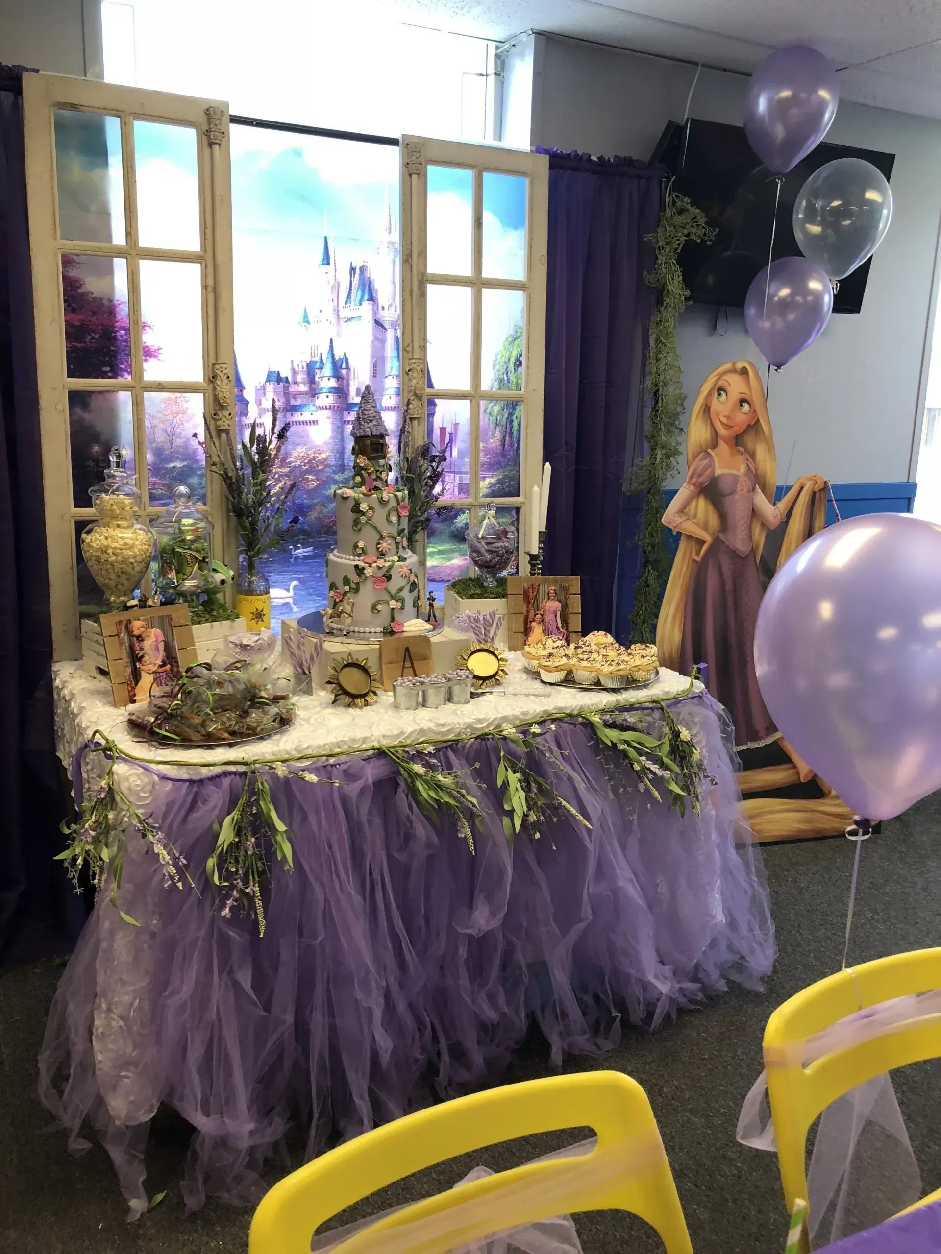 a purple table with balloons and a picture of rapunzel on it