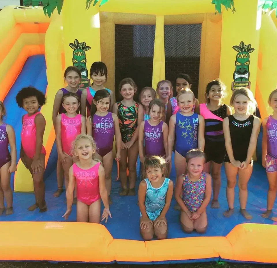 a group of young girls are posing for a picture in front of a bouncy house