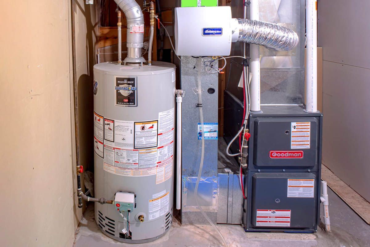 Water heater, air conditioning unit, and furnace in a basement setting. Gray appliances against a light background.