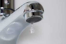Chrome faucet dripping water into a white sink.