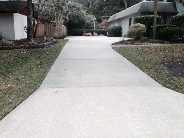 A concrete driveway leading to a house in a residential area