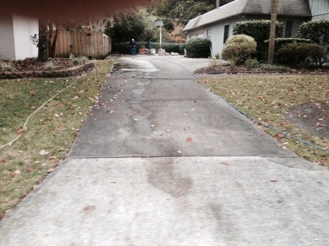 A concrete driveway with a house in the background