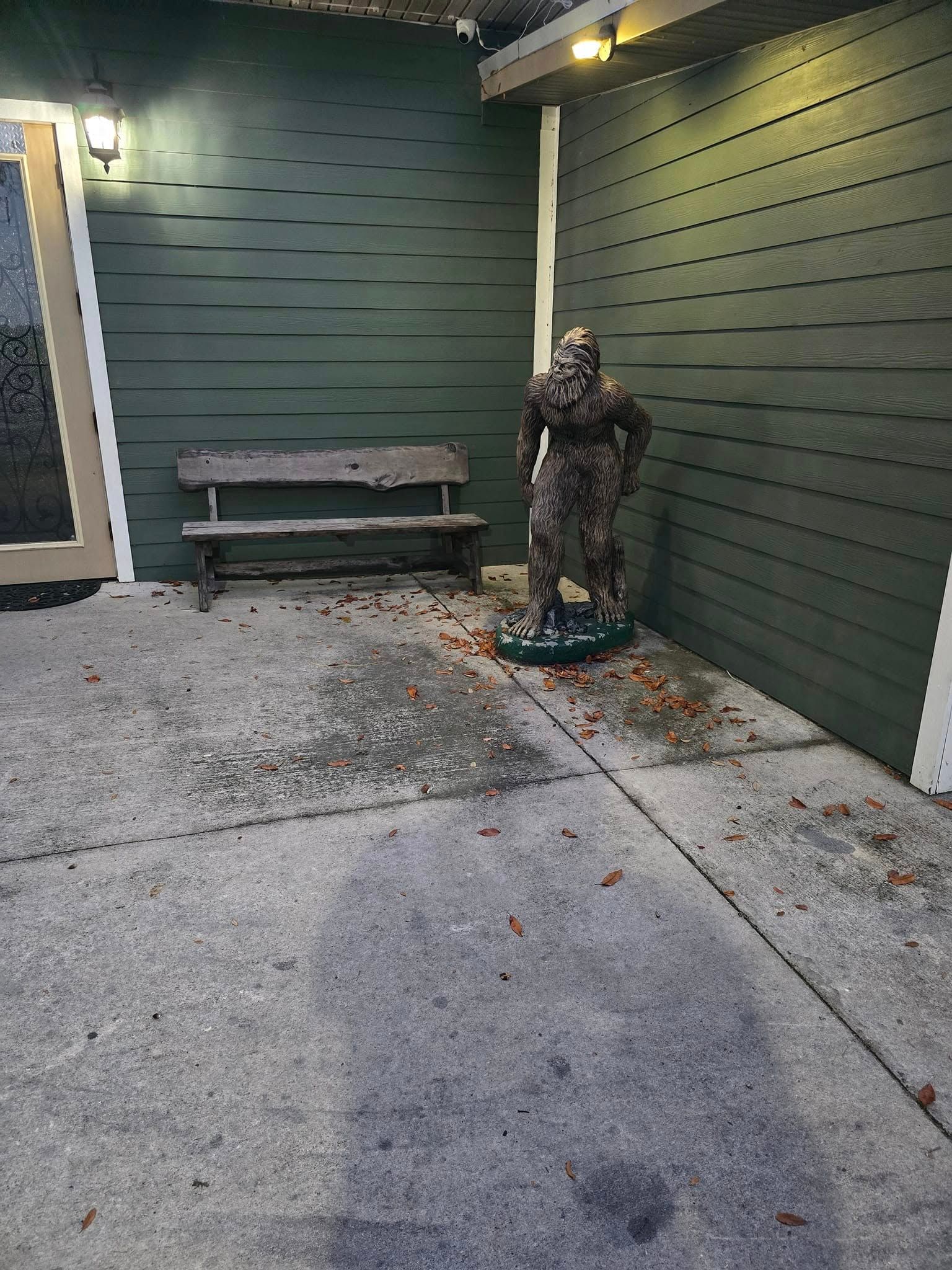 A statue of a man standing next to a wooden bench.