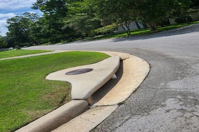 A curb on the side of a road with a manhole cover on it.