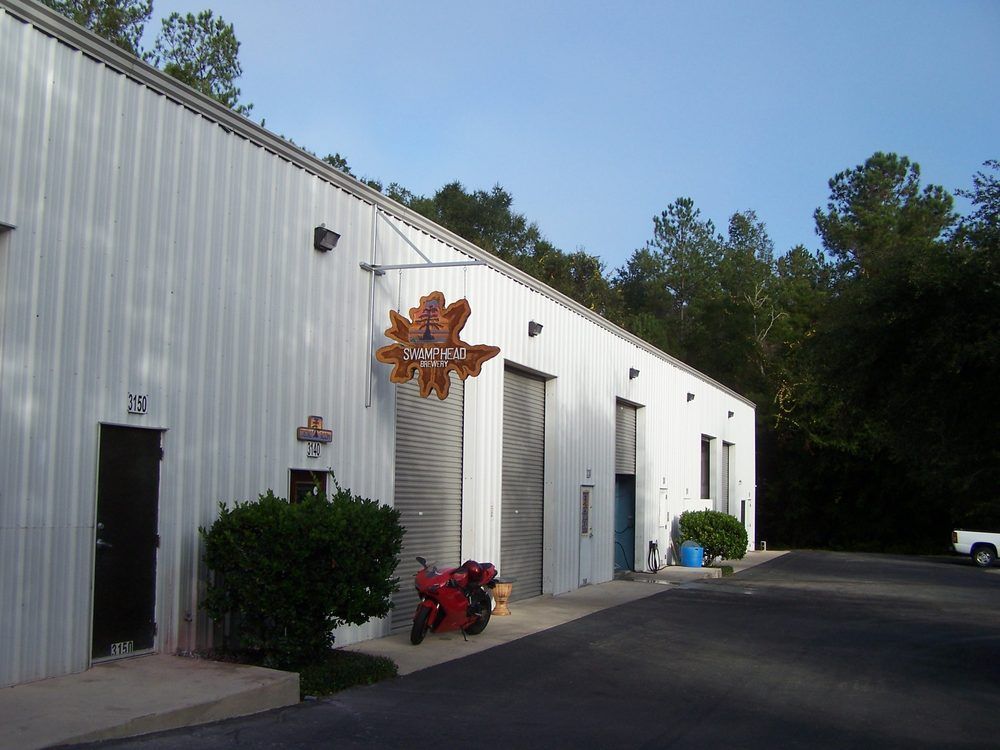 A red motorcycle is parked in front of a white building