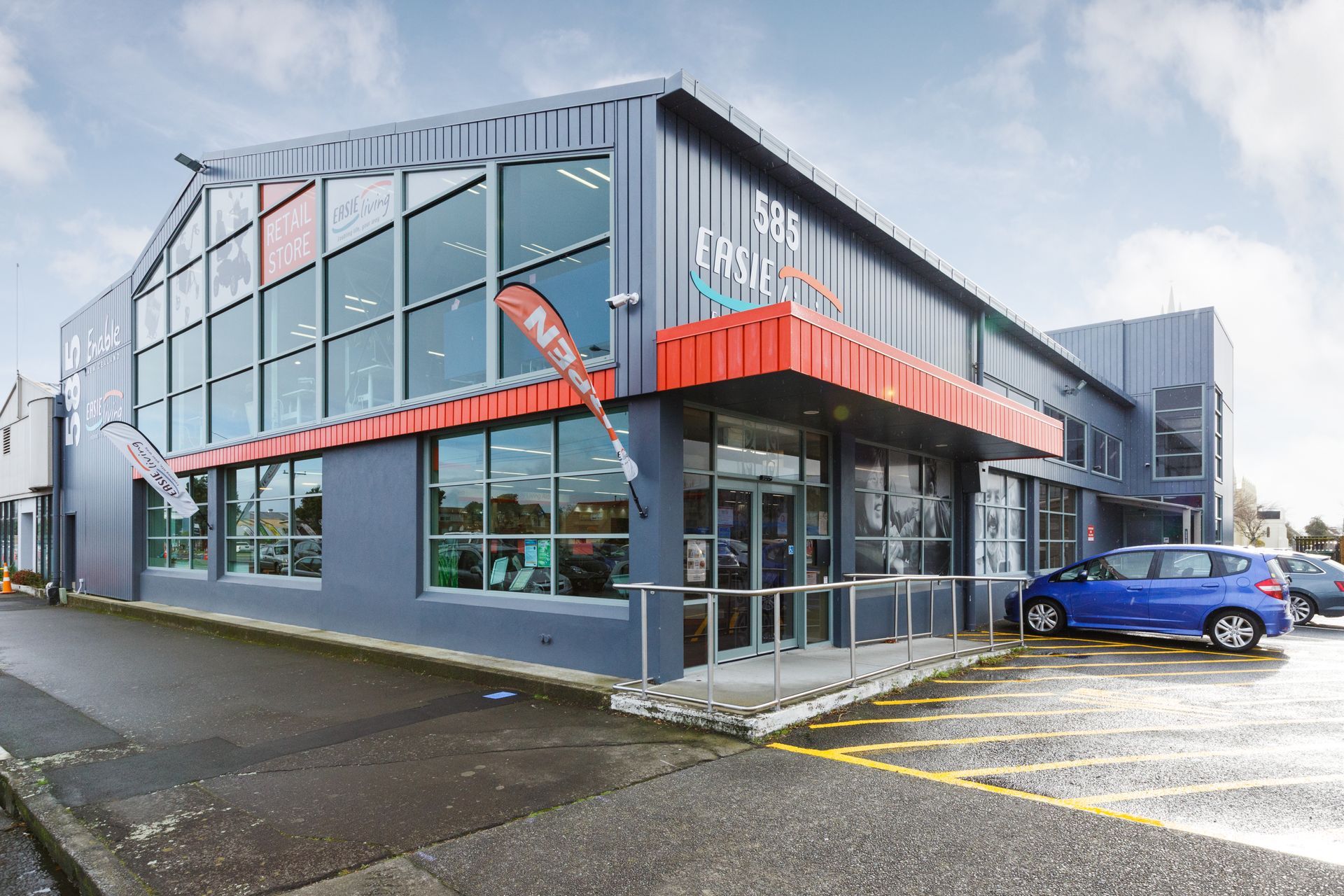 A large building with a lot of windows and a blue car parked in front of it.