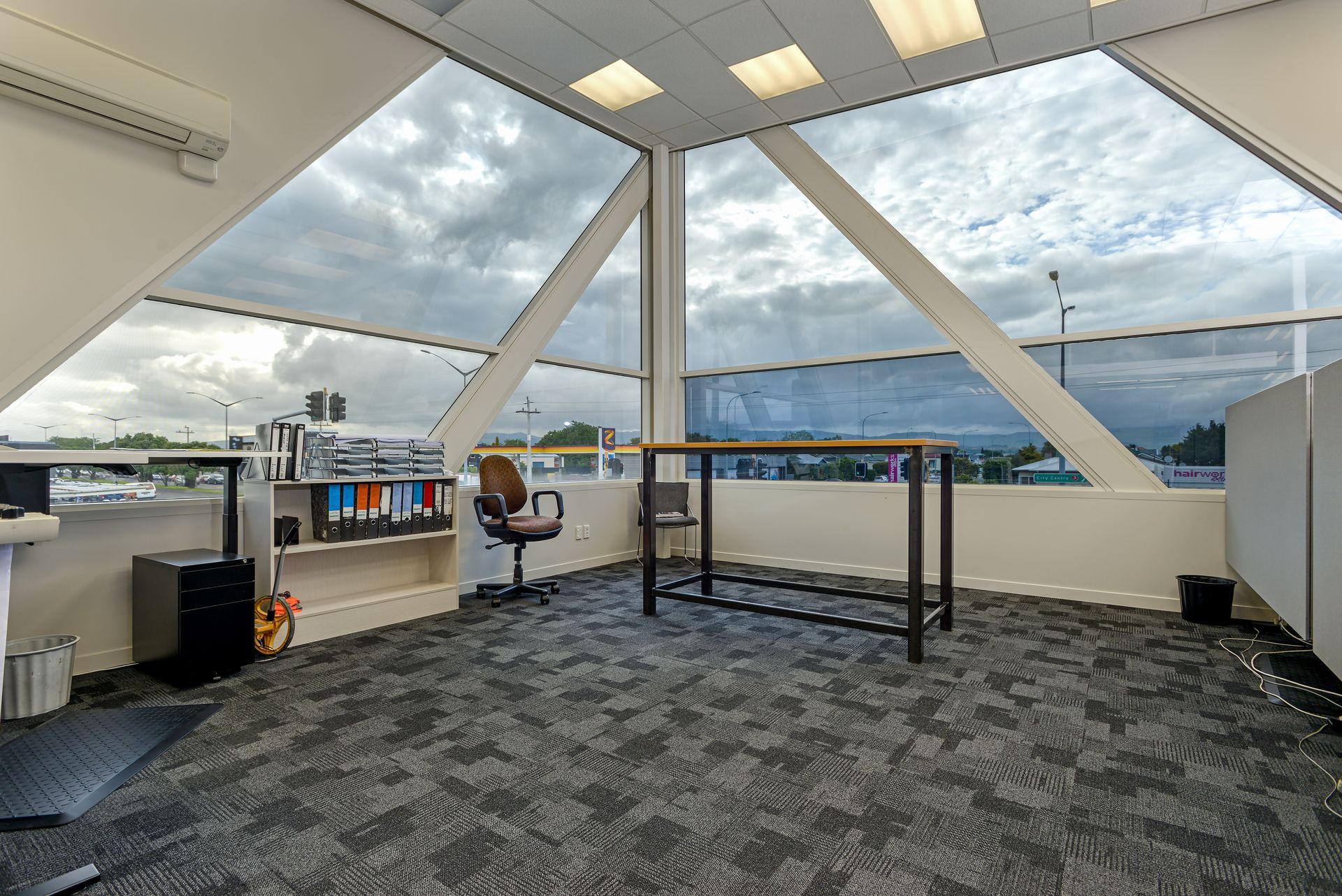 A room with a desk and chair in it and a lot of windows.