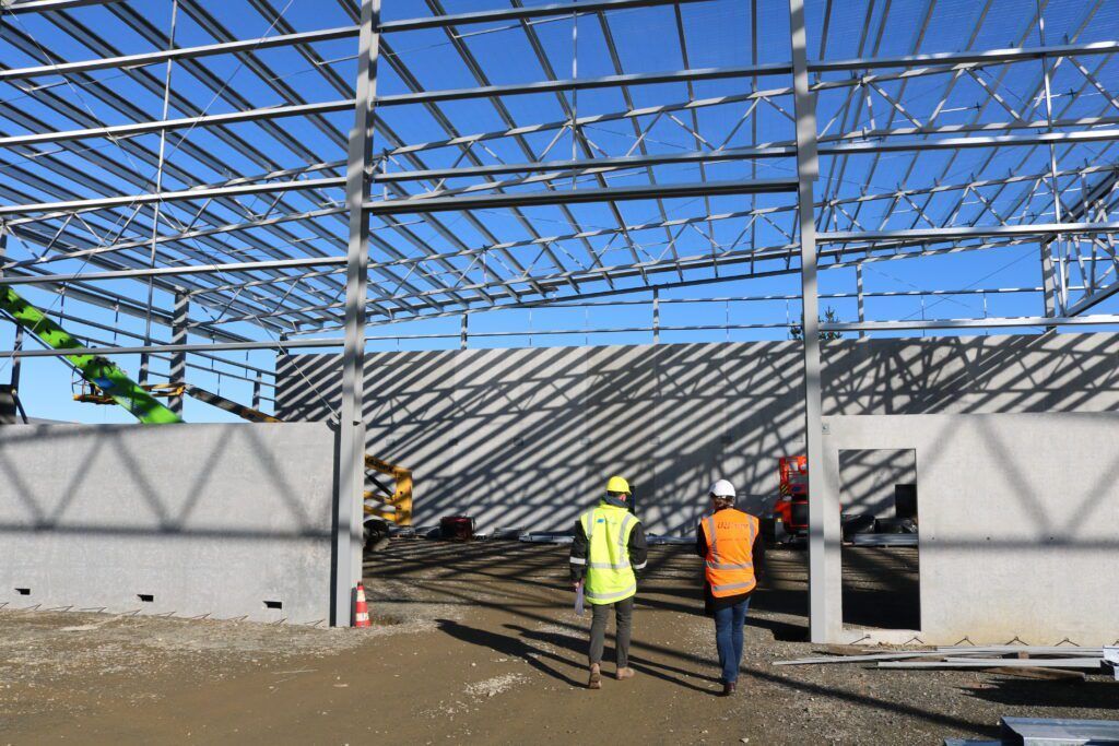 Two construction workers are standing in front of a building under construction.