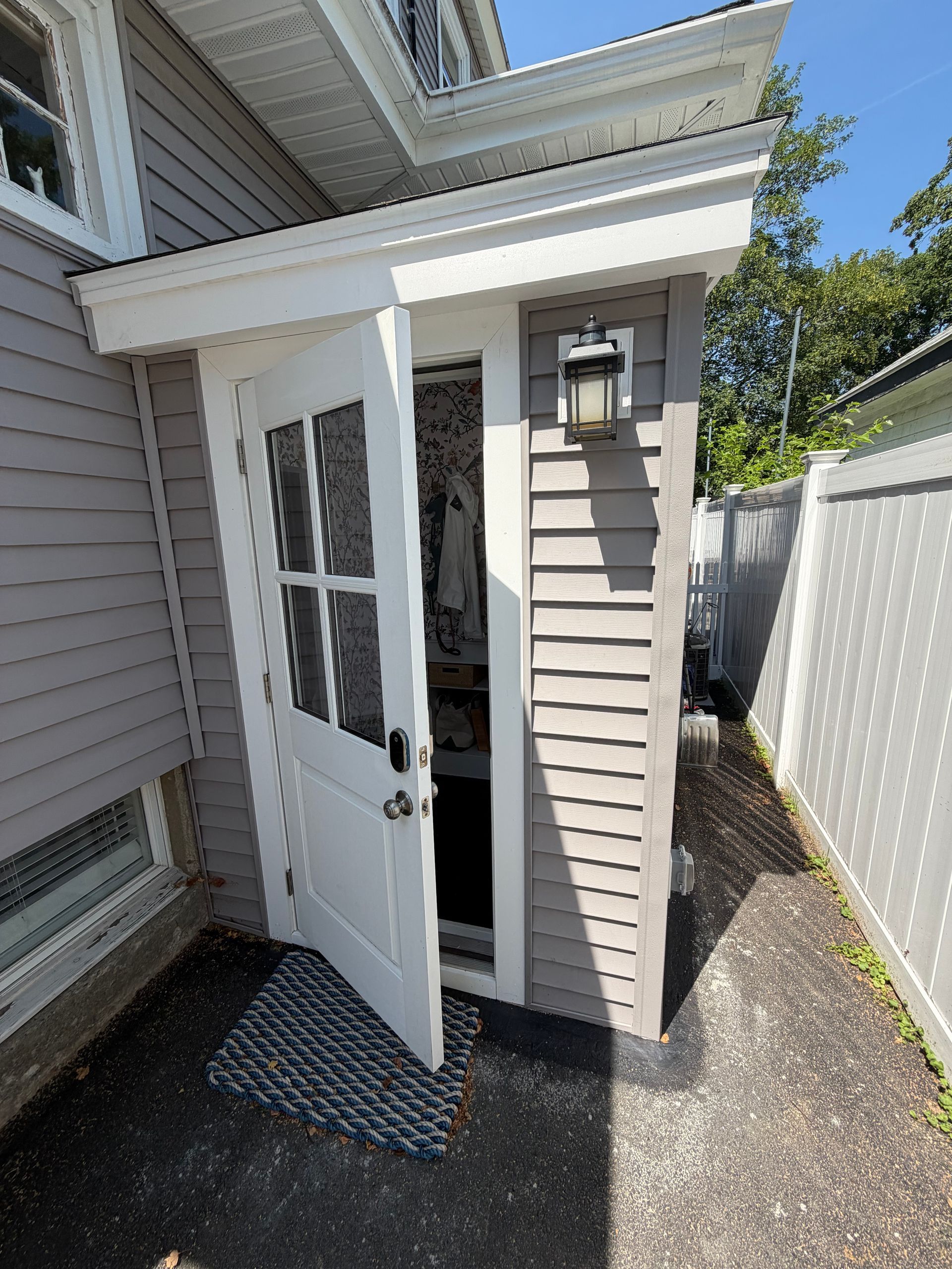 Exterior of a new mudroom addition with matching gray siding, covered entry roof, and lantern light fixture on a Winthrop, MA home