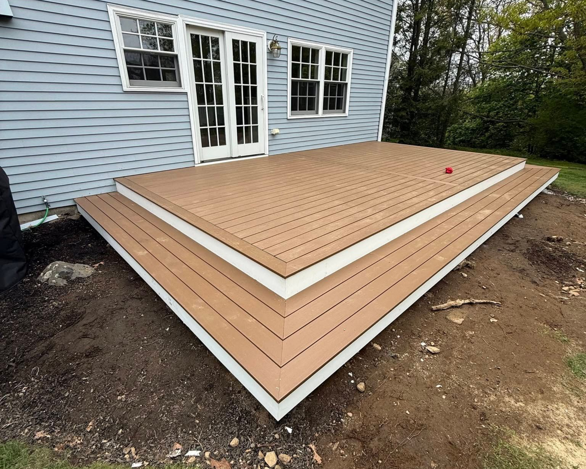 Completed composite deck with wraparound corner steps and white PVC fascia by A-Z Finish Carpentry in Marblehead MA