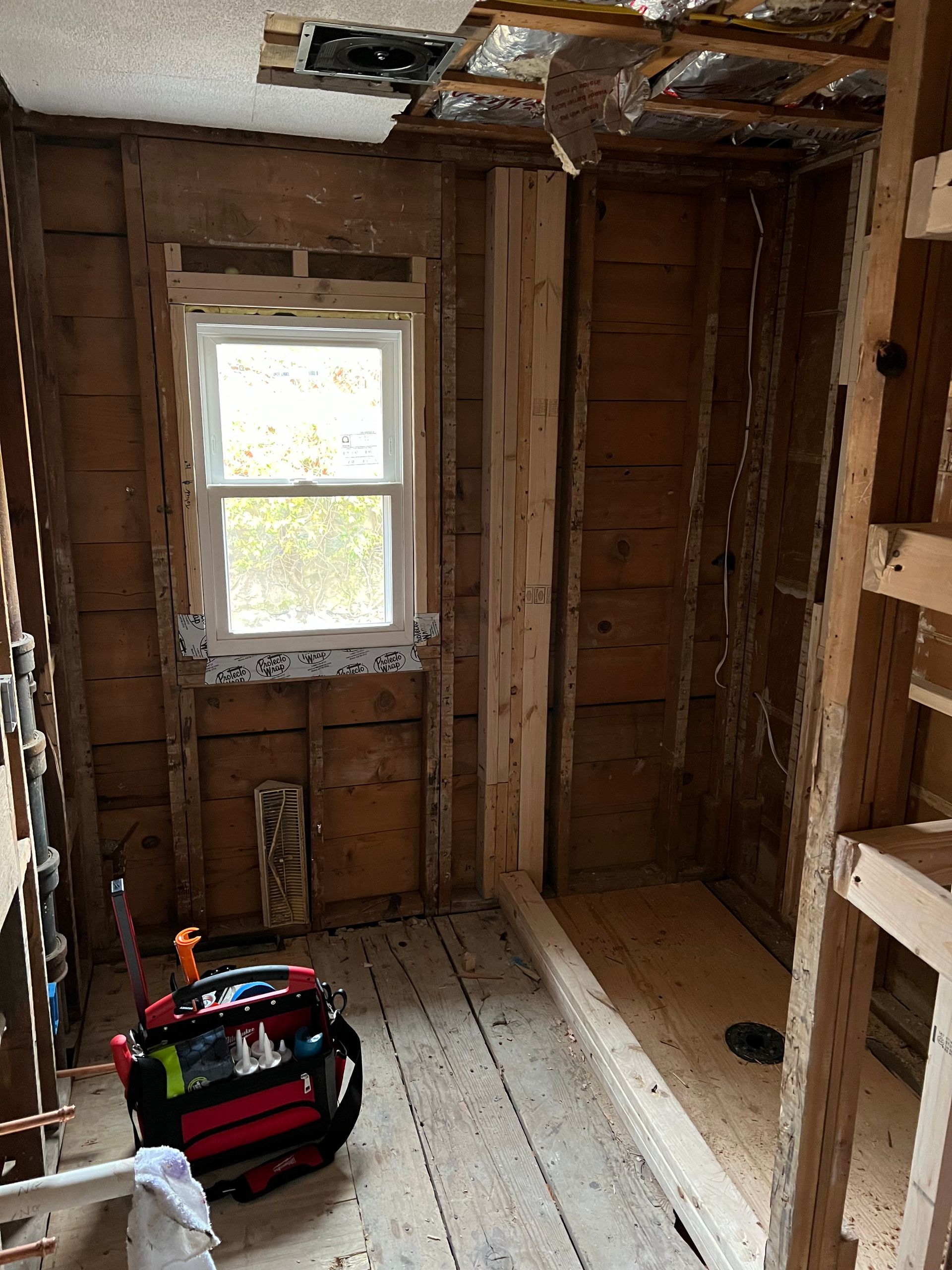 Outdated bathroom before remodel featuring white wall tiles with a red border, a basic white vanity, and red floor tiles.