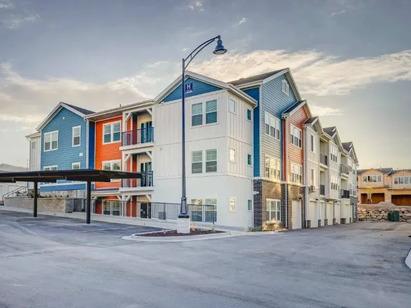 Exterior view of a colorful multi-building apartment community with a driveway and streetlamp.
