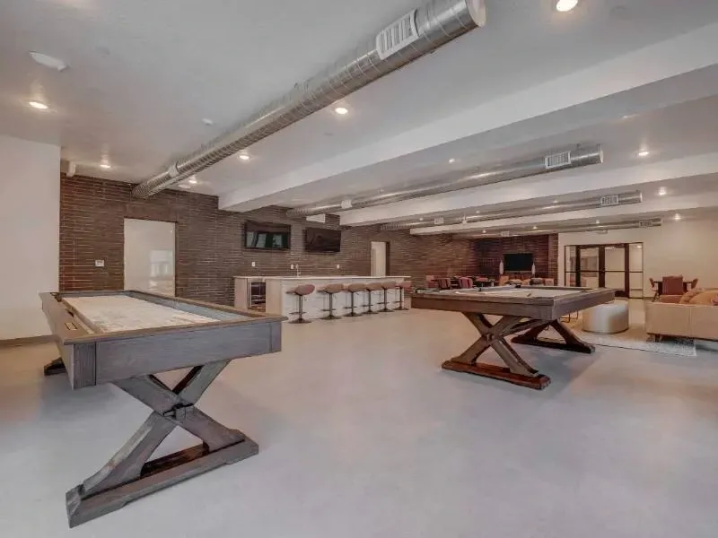 Indoor resident recreation area with billiards tables, bar stools, and lounge seating.