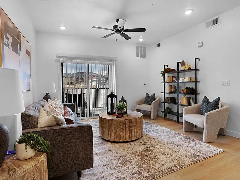 Living room in an apartment with a sofa, two chairs, and a balcony door.