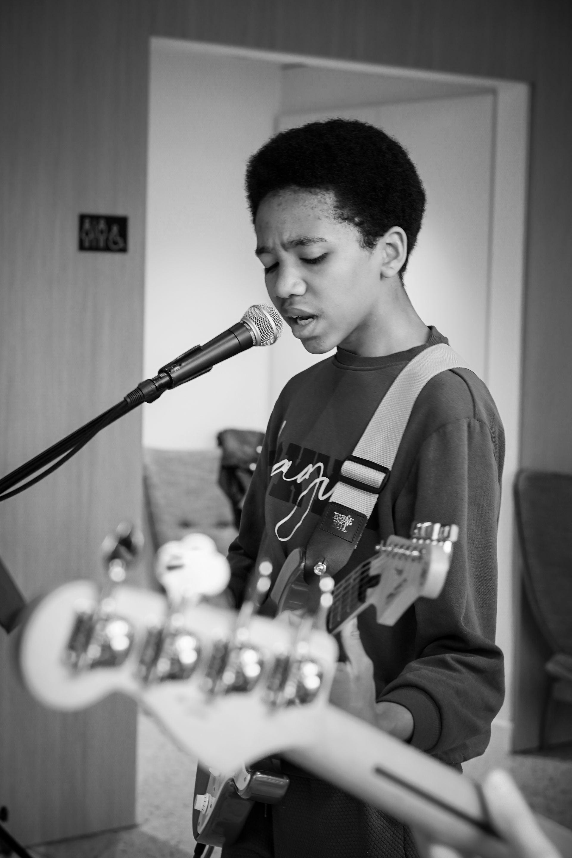 Person singing into a microphone while playing electric guitar in a room