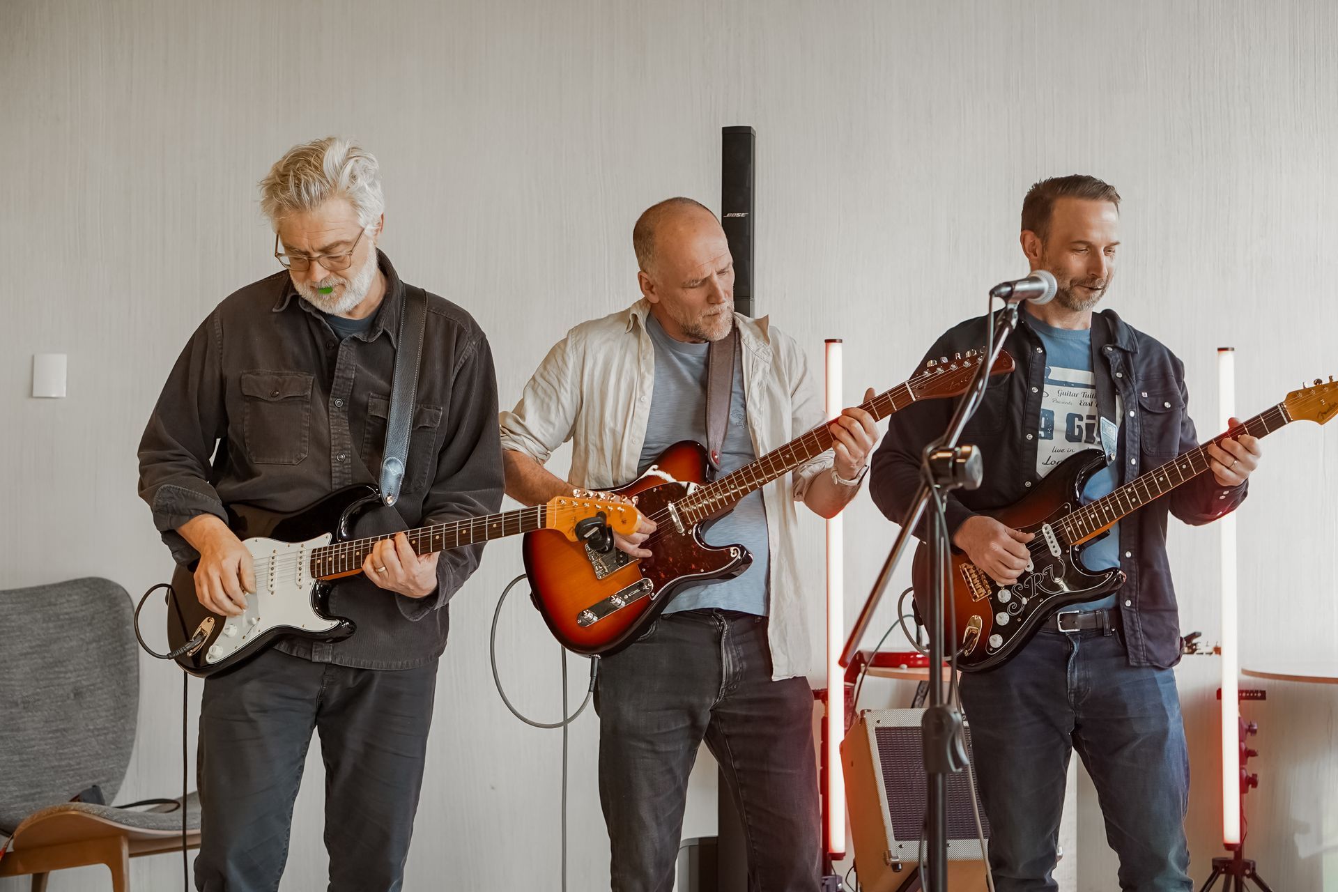 Three guitarists playing sunburst and black electric guitars