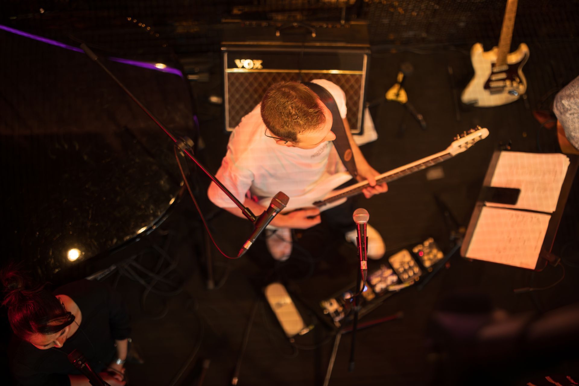 Person singing into a microphone while playing electric guitar in a room