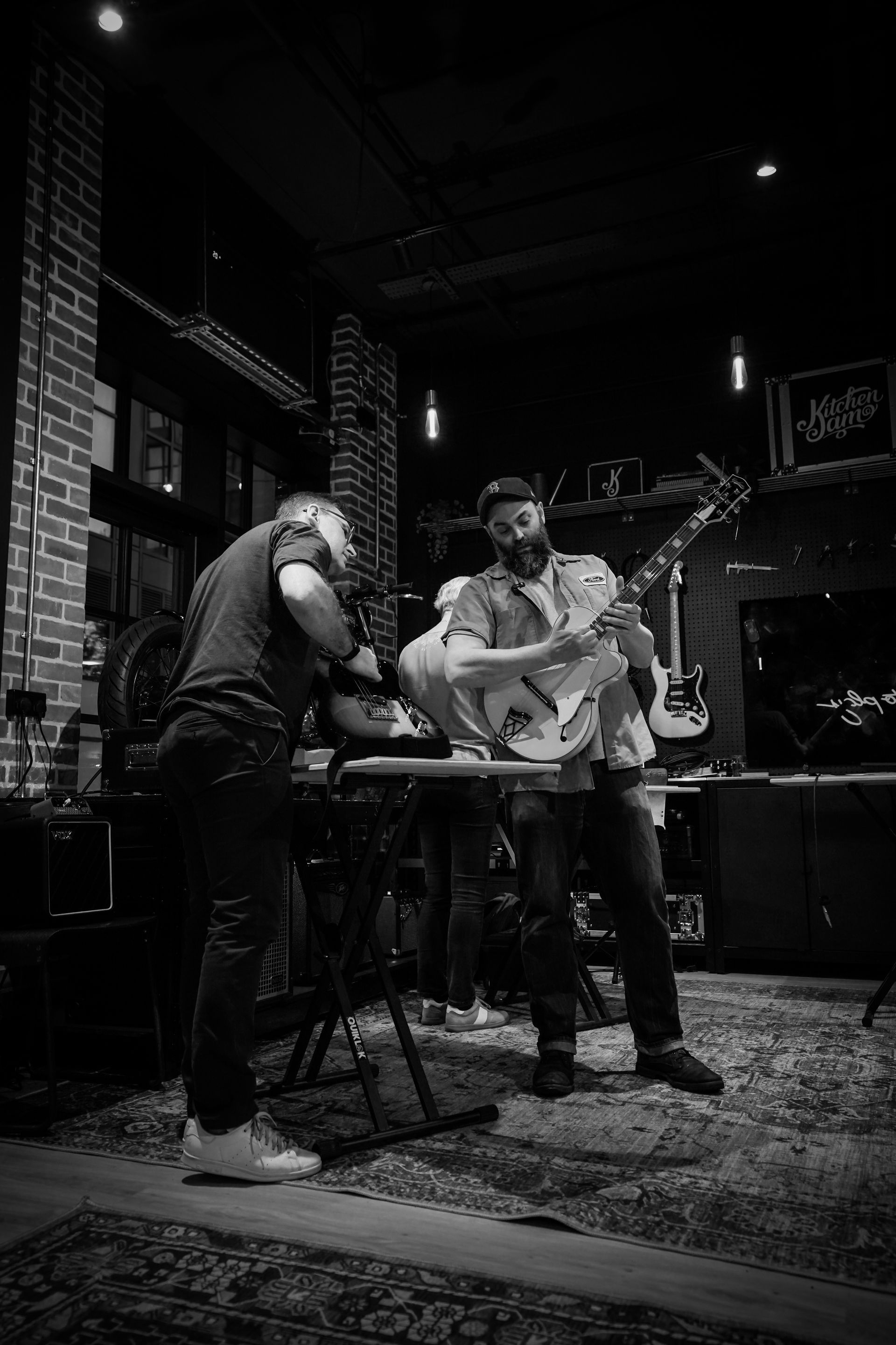 Workshop tutor showing a student how to adjust their guitar