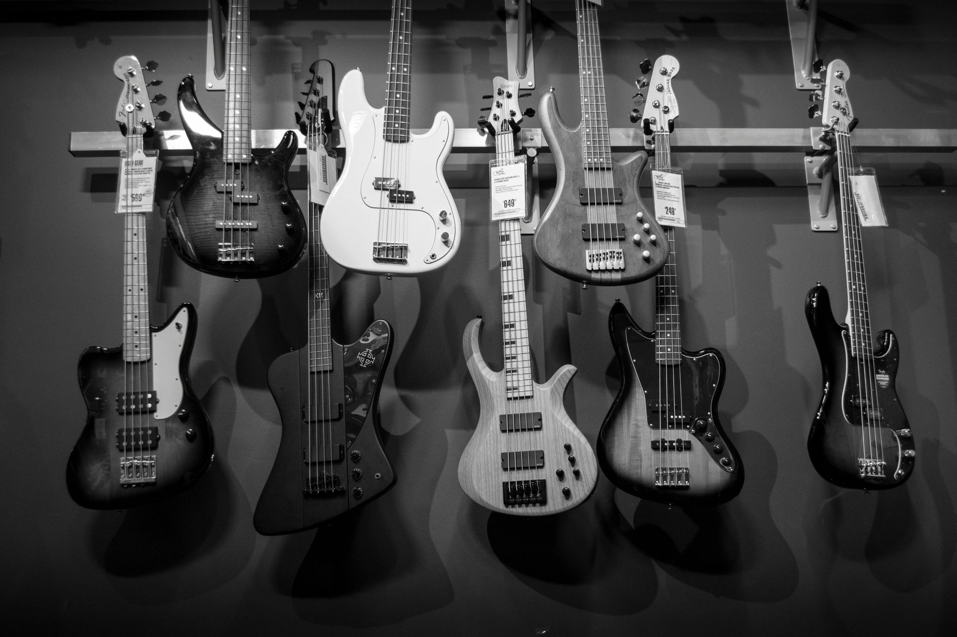 A black and white photo of a row of electric guitars hanging on a wall.