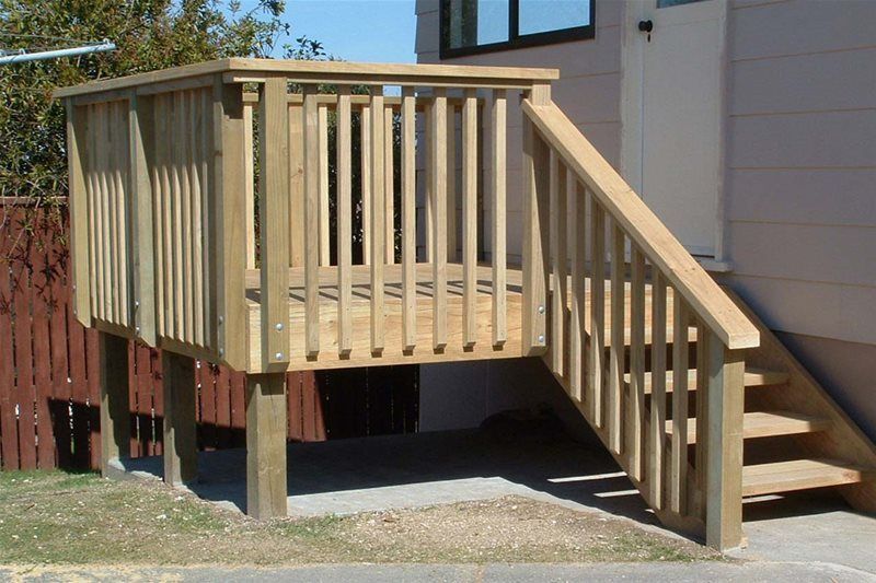 Wooden wheelchair ramp and landing attached to a house, with steps on the right.