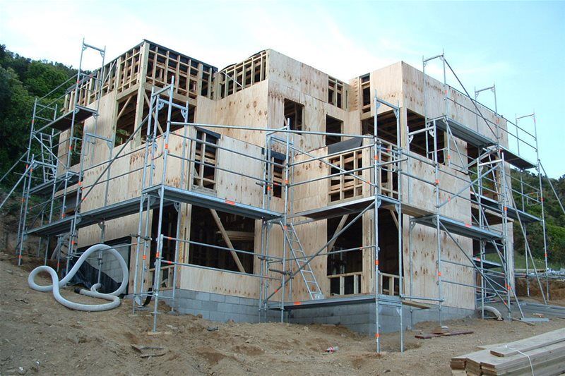 Partially built house with wooden framing and scaffolding on a construction site