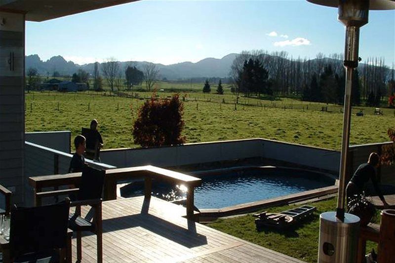 Sunny backyard patio with a small pool, two people, and mountains in the distance