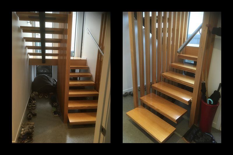 Wooden staircase with open risers and vertical slats in a narrow interior hallway