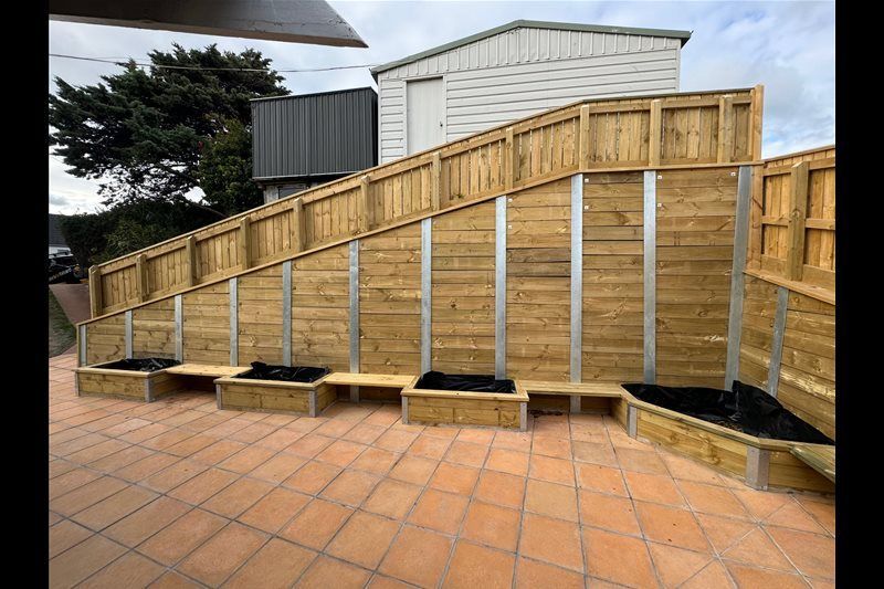 Wooden accessibility ramp with handrails on a tiled patio beside a building