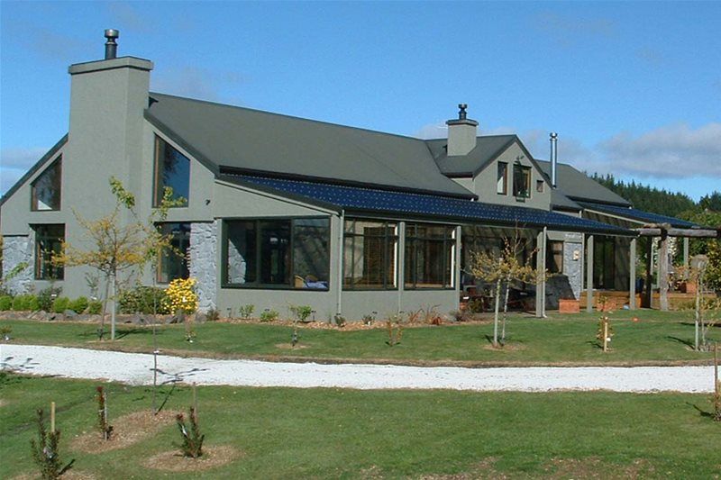 Modern house with gray roof, large windows, and landscaped lawn under a clear sky