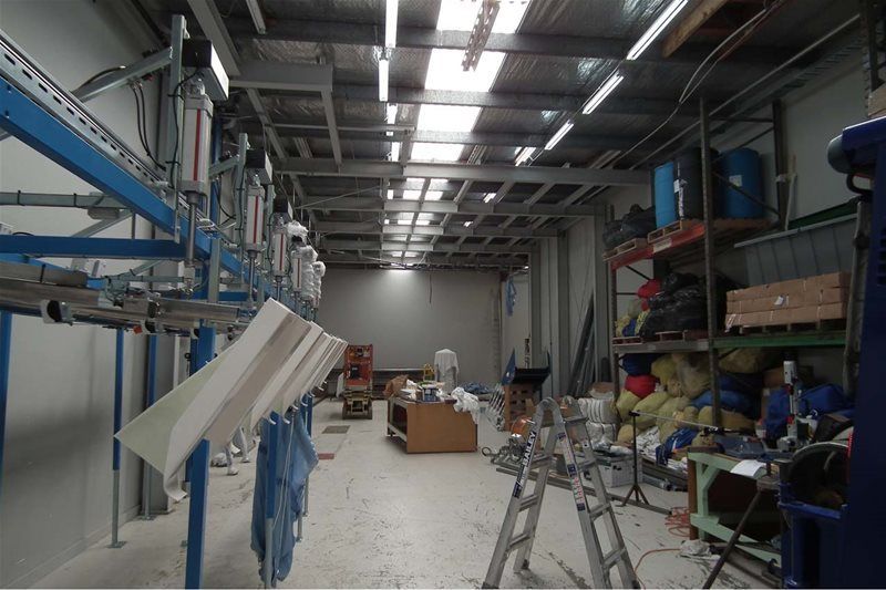 Industrial laundry room with blue conveyors, hanging garments, and shelves of supplies