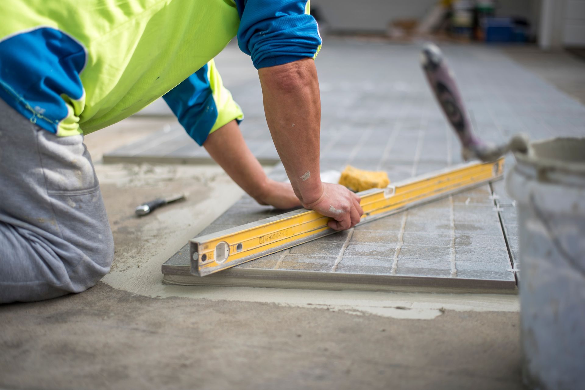 A man is measuring a tile floor with a level.