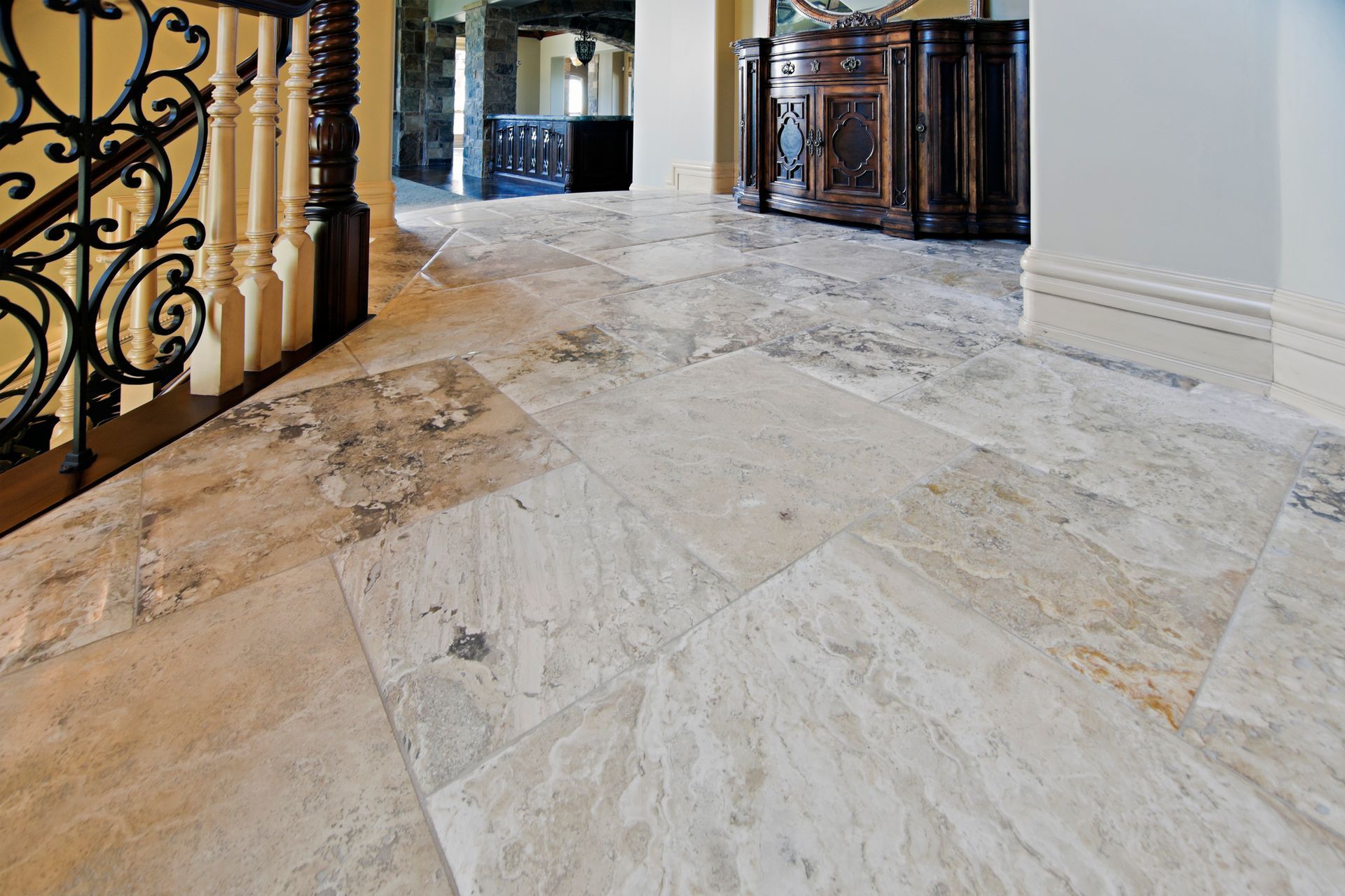 A marble floor in a hallway with a wrought iron railing.