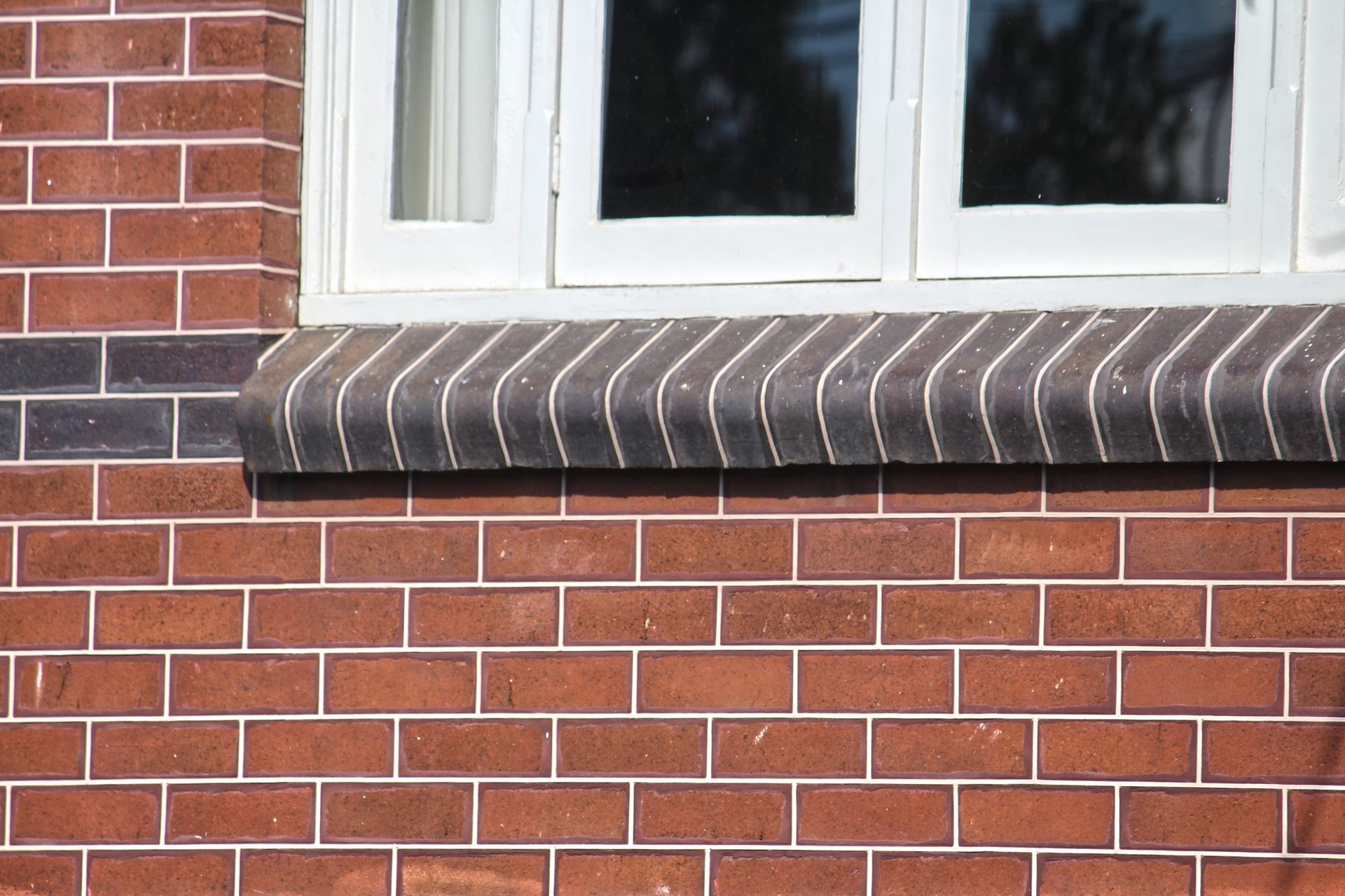 A red brick wall with a white window and a window sill.