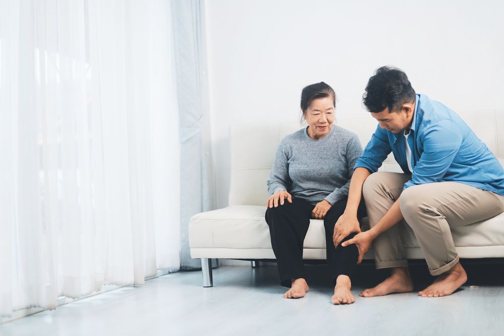 Two people sitting on a couch while one helps the other with a foot massage