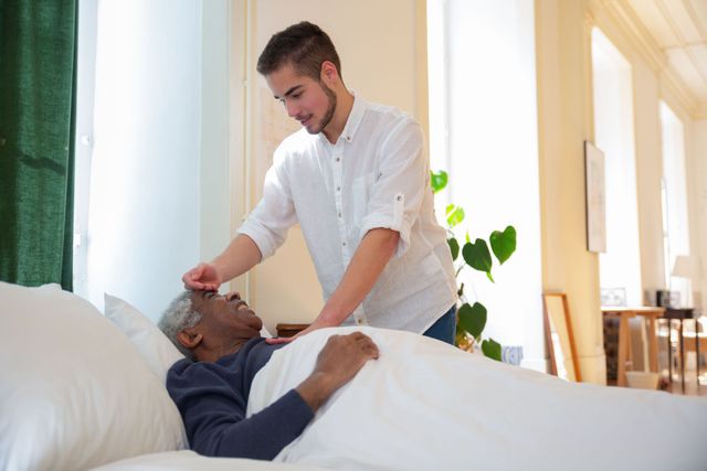 Caregiver checking the temperature of a person lying in bed in a bright room