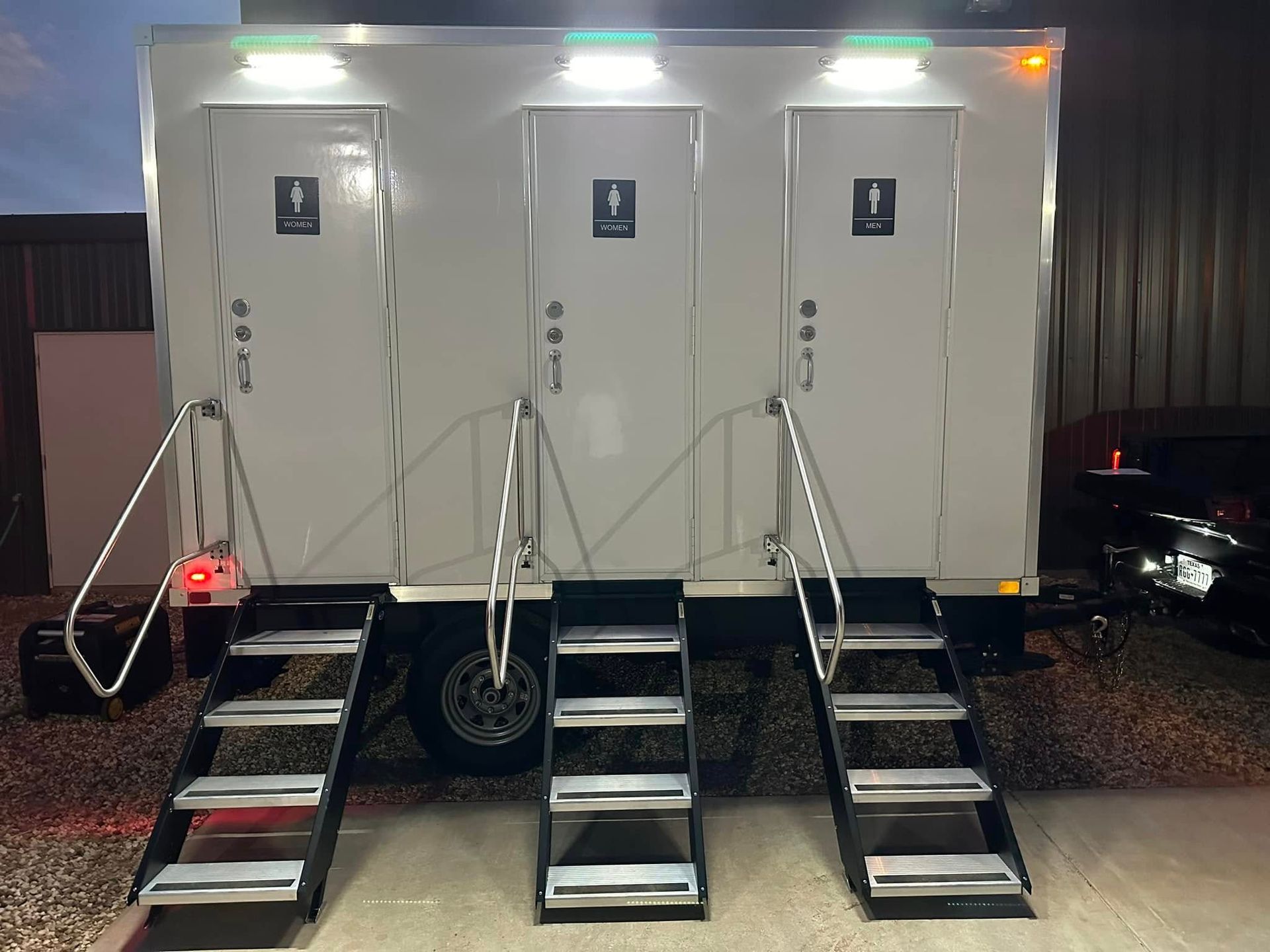 Portable restroom trailer with three individual stalls, each with stairs.