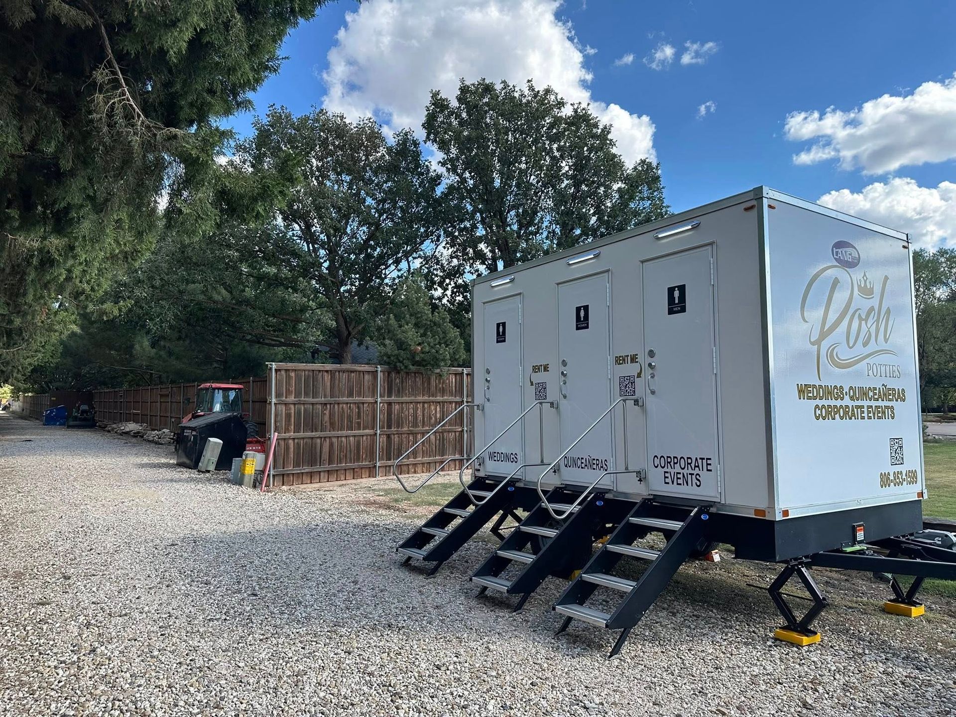 Portable restrooms on a trailer, with stairs. Located outdoors on gravel.