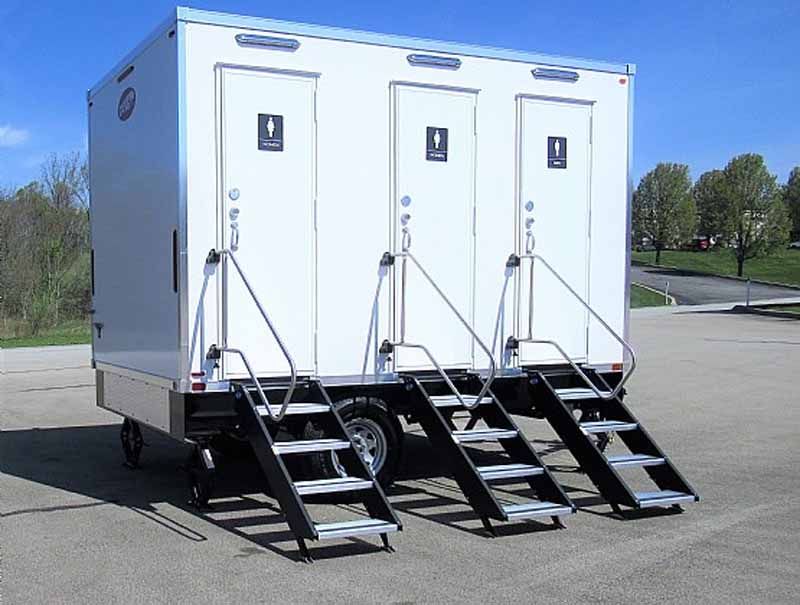 Portable restroom trailer with three individual stalls and attached staircases.