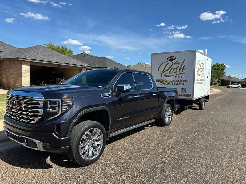 Dark blue GMC truck towing a white trailer with 