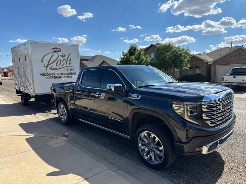 Black GMC pickup truck towing a white trailer with 