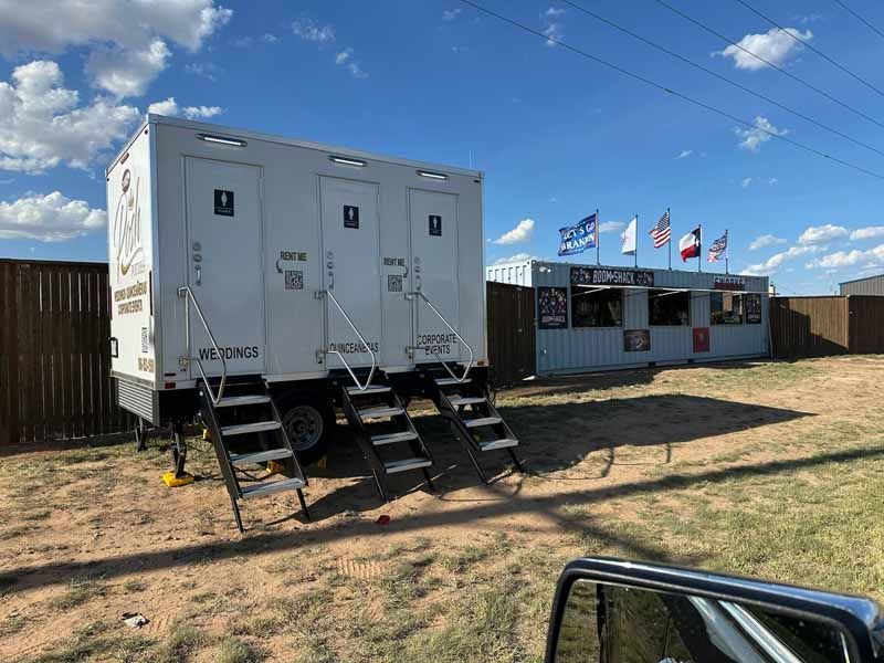 Portable restrooms next to a food stand, under a blue sky.