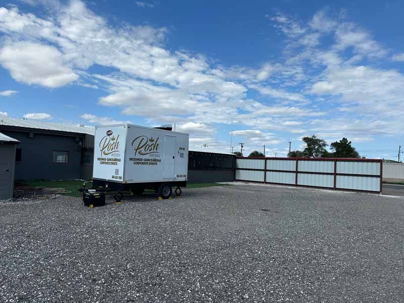 White mobile generator in a gravel lot with a fence and a cloudy sky.