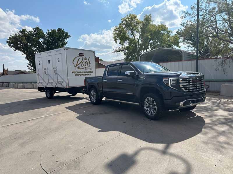 Black pickup truck towing a white trailer with the business name 